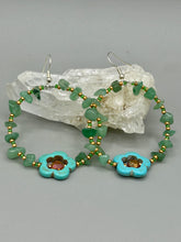 Load image into Gallery viewer, This pair of earrings features a turquoise magnesite floral bead with a vibrant orange glass bead and natural green aventurine stone chips juxtaposed against gold and blue glass beads. Measurements: 2" length