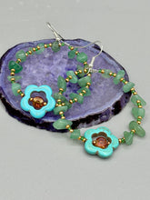 Load image into Gallery viewer, This pair of earrings features a turquoise magnesite floral bead with a vibrant orange glass bead and natural green aventurine stone chips juxtaposed against gold and blue glass beads. Measurements: 2" length