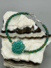 Load image into Gallery viewer, This blue-green pressed glass floral beaded bracelet is a nature-inspired accessory that adds a hint of summer to any look. Crafted with intricate green-blue pressed glass beads and metal wire, the bracelet has an iridescent shimmer finish and a lobster claw clasp for secure wear. Perfect for day-to-night looks.  Measurements:  Bracelet: 8 1/2" in length