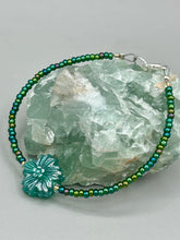 Load image into Gallery viewer, This blue-green pressed glass floral beaded bracelet is a nature-inspired accessory that adds a hint of summer to any look. Crafted with intricate green-blue pressed glass beads and metal wire, the bracelet has an iridescent shimmer finish and a lobster claw clasp for secure wear. Perfect for day-to-night looks.  Measurements:  Bracelet: 8 1/2" in length