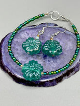 Load image into Gallery viewer, This blue-green pressed glass floral beaded bracelet is a nature-inspired accessory that adds a hint of summer to any look. Crafted with intricate green-blue pressed glass beads and metal wire, the bracelet has an iridescent shimmer finish and a lobster claw clasp for secure wear. Perfect for day-to-night looks.  Measurements:  Bracelet: 8 1/2" in length