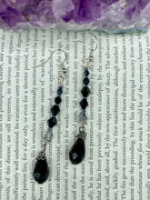 Load image into Gallery viewer, These shimmering black and silver glass beaded earrings feature a large black teardrop glass bead for added movement. This sophisticated and versatile accessory can be worn for an elegant evening look, brunch ensemble, wedding necklace, or minimalist style. Measurements: 2 1/2” in length