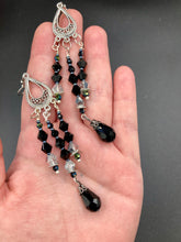 Load image into Gallery viewer, This stylish three-strand black and silver glass beaded earring design presents a beautiful dancing effect, boasting a large black teardrop glass bead. A versatile accessory, it suits a variety of ensembles from cocktail chic to wedding fineries, and its minimalist aesthetic lends a modern charm.  Measurements: 3 3/4” in length