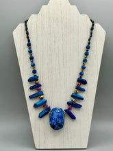Load image into Gallery viewer, Powerful statement piece necklace features an eye-catching hand sculpted dark blue clay scarab beetle pendant. Adorned with vibrant sapphire luster quartz nuggets and sapphire faceted glass beaded necklace, this dramatic necklace artfully wraps around the neck, conveying an elegant and bold style. The Egyptian scarab symbol of rebirth, regeneration, and protection in the afterlife. Secure toggle clasp - Necklace is 23" length