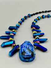 Load image into Gallery viewer, Powerful statement piece necklace features an eye-catching hand sculpted dark blue clay scarab beetle pendant. Adorned with vibrant sapphire luster quartz nuggets and sapphire faceted glass beaded necklace, this dramatic necklace artfully wraps around the neck, conveying an elegant and bold style. The Egyptian scarab symbol of rebirth, regeneration, and protection in the afterlife. Secure toggle clasp - Necklace is 23" length