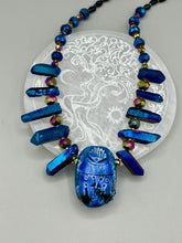 Load image into Gallery viewer, Powerful statement piece necklace features an eye-catching hand sculpted dark blue clay scarab beetle pendant. Adorned with vibrant sapphire luster quartz nuggets and sapphire faceted glass beaded necklace, this dramatic necklace artfully wraps around the neck, conveying an elegant and bold style. The Egyptian scarab symbol of rebirth, regeneration, and protection in the afterlife. Secure toggle clasp - Necklace is 23" length