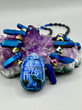 Load image into Gallery viewer, Powerful statement piece necklace features an eye-catching hand sculpted dark blue clay scarab beetle pendant. Adorned with vibrant sapphire luster quartz nuggets and sapphire faceted glass beaded necklace, this dramatic necklace artfully wraps around the neck, conveying an elegant and bold style. The Egyptian scarab symbol of rebirth, regeneration, and protection in the afterlife. Secure toggle clasp - Necklace is 23" length