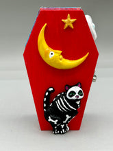 Load image into Gallery viewer, Coffin keepsake box represents the eternal love for a special kitty cat in your life. Cat silhouette sitting admiring the moon and stars. Day Of The Dead art was created for the cat lovers who adore their sweet kitty. Coffin-shaped box features a bright and vibrant red exterior, with an adoring yellow crescent moon and star. Complemented with a shimmery blue ribbon and smiling moon, the inside is painted in a bright bluer hue with black floral cross and detailing a traditional Mexican-themed fabric.