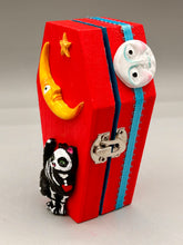 Load image into Gallery viewer, Coffin keepsake box represents the eternal love for a special kitty cat in your life. Cat silhouette sitting admiring the moon and stars. Day Of The Dead art was created for the cat lovers who adore their sweet kitty. Coffin-shaped box features a bright and vibrant red exterior, with an adoring yellow crescent moon and star. Complemented with a shimmery blue ribbon and smiling moon, the inside is painted in a bright bluer hue with black floral cross and detailing a traditional Mexican-themed fabric.