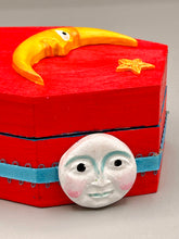 Load image into Gallery viewer, Coffin keepsake box represents the eternal love for a special kitty cat in your life. Cat silhouette sitting admiring the moon and stars. Day Of The Dead art was created for the cat lovers who adore their sweet kitty. Coffin-shaped box features a bright and vibrant red exterior, with an adoring yellow crescent moon and star. Complemented with a shimmery blue ribbon and smiling moon, the inside is painted in a bright bluer hue with black floral cross and detailing a traditional Mexican-themed fabric.