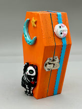 Load image into Gallery viewer, Coffin keepsake box represents the eternal love for a special kitty cat in your life. Cat silhouette sitting admiring the moon and stars. Day Of The Dead art was created for the cat lovers who adore their sweet kitty. Coffin-shaped box features a bright and vibrant orange exterior, with an adoring blue crescent moon and yellow star. Complemented with a shimmery blue ribbon and smiling moon, the inside is painted in a bright blue hue with black floral cross and detailing a traditional Mexican-themed fabric.
