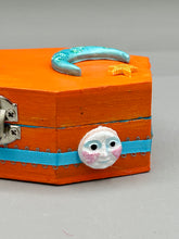 Load image into Gallery viewer, Coffin keepsake box represents the eternal love for a special kitty cat in your life. Cat silhouette sitting admiring the moon and stars. Day Of The Dead art was created for the cat lovers who adore their sweet kitty. Coffin-shaped box features a bright and vibrant orange exterior, with an adoring blue crescent moon and yellow star. Complemented with a shimmery blue ribbon and smiling moon, the inside is painted in a bright blue hue with black floral cross and detailing a traditional Mexican-themed fabric.