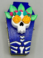 Load image into Gallery viewer, This coffin-shaped box features a bright and colorful exterior, showcasing a vibrant Frida Kahlo inspired calavera. This beautifully handcrafted calavera is adorned with Frida's iconic floral crown. To complete the look, the inside is also painted in colorful hues with a black and silver floral cross. The interior is also finished with a traditional Mexican-themed fabric. L: 4 1/2“; W: 2 ½”; H: 1 5/8”