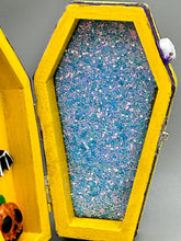 Load image into Gallery viewer, Coffin shaped box features a Day of the Dead kitty cat wearing a cute witchy hat while standing next to her witchy broom and a flying bat friend. The inside of the coffin is adorned with a witchy crescent moon, Jack-O-Lantern and a cute bat. This captivating coffin box makes an eye-catching, bewitching and whimsical Halloween-themed art piece that adds a one-of-a-kind Halloween touch to any home or office. L: 4 7/8"; W: 3"; H: 1 1/2"