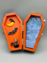Load image into Gallery viewer, Coffin shaped box features a Day of the Dead kitty cat wearing a cute witchy hat while standing next to her witchy broom and her flying bat friend. The inside of the coffin is adorned with a witchy crescent moon, Jack-O-Lantern and a cute Day of the Dead tiny kitten. This captivating coffin box makes an eye-catching, bewitching and whimsical Halloween-themed art piece that adds a one-of-a-kind Halloween touch to any home or office.
