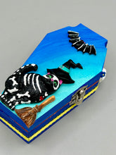 Load image into Gallery viewer, Coffin shaped box features a Day of the Dead kitty cat wearing a cute witchy hat while standing next to her witchy broom and her flying bat friend. The inside of the coffin is adorned with a witchy crescent moon, Jack-O-Lantern and a cute Day of the Dead tiny kitten. This captivating coffin box makes an eye-catching, bewitching and whimsical Halloween-themed art piece that adds a one-of-a-kind Halloween touch to any home or office.