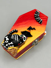 Load image into Gallery viewer, Coffin shaped box features a Day of the Dead kitty cat wearing a cute witchy hat while standing next to her witchy broom and her flying bat friend. The inside of the coffin is adorned with a witchy crescent moon, Jack-O-Lantern and a cute bat. This captivating coffin box makes an eye-catching, bewitching and whimsical Halloween-themed art piece that adds a one-of-a-kind Halloween touch to any home or office.