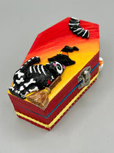 Load image into Gallery viewer, Coffin shaped box features a Day of the Dead kitty cat wearing a cute witchy hat while standing next to her witchy broom and her flying bat friend. The inside of the coffin is adorned with a witchy crescent moon, Jack-O-Lantern and a cute bat. This captivating coffin box makes an eye-catching, bewitching and whimsical Halloween-themed art piece that adds a one-of-a-kind Halloween touch to any home or office.