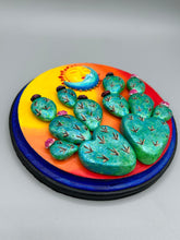 Load image into Gallery viewer, Southwest inspired wall art comes in a circle-shaped wood frame with a sun and crescent moon motifs. Its warm sky hues, including yellow, orange and dark red, are further complemented by hand sculpted cacti plants with cool green-blue tones with light and dark pink flowers. Diameter 6 3/4"