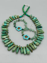 Load image into Gallery viewer, This pair of earrings features a turquoise magnesite floral bead with a vibrant orange glass bead and natural green aventurine stone chips juxtaposed against gold and blue glass beads. Measurements: 2" length