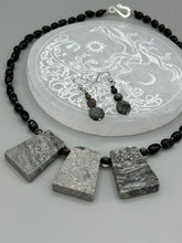 Load image into Gallery viewer, These earrings are crafted with turmaline quartz, snowflake obsidian and black glass beads, creating a neutral cool look that is both unique and adaptable to any style. Measurements: 1 1/2” in length