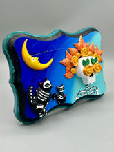 Load image into Gallery viewer, La Catrina y Gatita wall art is the purrfect hanging Day of the Dead art piece to add to your ofrenda. A tribute to an unbreakable bond and eternal love between cats and their guardians. Featuring a vibrant and intricate detail catrina and her floral crown accompanied by her beloved kitty cat. This Day of the Dead-inspired artwork adds a little touch of Mexican art to your home or office. A unique handcrafted gift for any cat lover. Measurements: H 5" x W 7” x D 1 1/2"