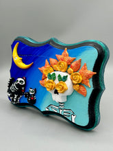 Load image into Gallery viewer, La Catrina y Gatita wall art is the purrfect hanging Day of the Dead art piece to add to your ofrenda. A tribute to an unbreakable bond and eternal love between cats and their guardians. Featuring a vibrant and intricate detail catrina and her floral crown accompanied by her beloved kitty cat. This Day of the Dead-inspired artwork adds a little touch of Mexican art to your home or office. A unique handcrafted gift for any cat lover. Measurements: H 5" x W 7” x D 1 1/2"