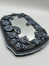 Load image into Gallery viewer, Make a bold statement with this handcrafted Goth Floral Decorative Mirror Wall Art Decor. The wood frame is complimented with highly detailed flowers, leaf and vine motifs, enhanced with shimmery metallic highlights for added texture and depth. Each intricate detail is carefully sculpted to create a unique and beautiful piece that's sure to make a statement. H 6 3/4" x W 9 1/2” x D 1"