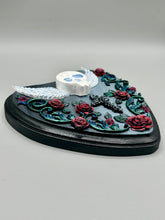 Load image into Gallery viewer, This Memento Mori Wall Art Decor is a one-of-a-kind art piece, skillfully crafted with a polymer clay skull and wings on a dark gray hear shape wood frame, decoratively woven with dark red roses and vines. It's perfect for adding an eye-catching touch to any wall and makes a unique, bold gift. W 6 1/2" x H 6 3/4"x D1 1/2"