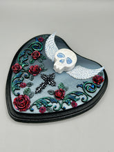 Load image into Gallery viewer, This Memento Mori Wall Art Decor is a one-of-a-kind art piece, skillfully crafted with a polymer clay skull and wings on a dark gray hear shape wood frame, decoratively woven with dark red roses and vines. It's perfect for adding an eye-catching touch to any wall and makes a unique, bold gift. W 6 1/2" x H 6 3/4"x D1 1/2"