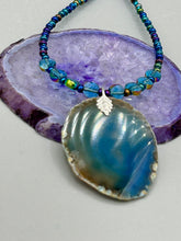 Load image into Gallery viewer, This Dark Blue Agate Geode Sliced Stone Chip Necklace is a luxurious addition to any jewelry collection. It features bold, eye-catching dark blue agate geode in an earthy outline, suspended on a unique glass beaded necklace that contains a mixture of blue and purple glass beads with a beautiful iridescence. This necklace is the perfect boho chic accent to take any look to the next level.   Measurements:    Necklace is 18” in length - pendant is 1 3/4” Height