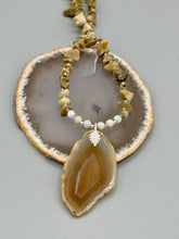 Load image into Gallery viewer, This Light Brown Banded Agate Geode Sliced Stone Chip Necklace is a luxurious addition to any jewelry collection. It features natural, light brown agate banded geode in a luxurious earth-tone. Suspended on a unique strand of natural bamboo chips and gold and clear beaded necklace. The combination of neutral colors and nature inspired design makes them the perfect accessory for any outfit. Measurements: Necklace is 18” in length - pendant is 2” Height