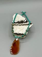 Load image into Gallery viewer, This unique and luxurious Amber Tone Agate Geode Sliced Stone Chip Necklace is a one-of-a-kind statement piece crafted from natural gemstones. The necklace features an amber-tone banded geode, suspended from a strand of blue and green turquoise and gold glass beads, and blue-green magnesite stone beads. This stylish boho-chic accessory is perfect for any casual or formal occasion. Measurements: Necklace is 18” in length - pendant is 2 1/2” Height