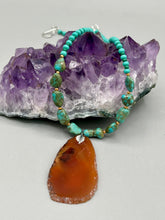 Load image into Gallery viewer, This unique and luxurious Amber Tone Agate Geode Sliced Stone Chip Necklace is a one-of-a-kind statement piece crafted from natural gemstones. The necklace features an amber-tone banded geode, suspended from a strand of blue and green turquoise and gold glass beads, and blue-green magnesite stone beads. This stylish boho-chic accessory is perfect for any casual or formal occasion. Measurements: Necklace is 18” in length - pendant is 2 1/2” Height
