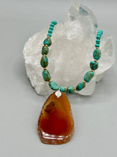 Load image into Gallery viewer, This unique and luxurious Amber Tone Agate Geode Sliced Stone Chip Necklace is a one-of-a-kind statement piece crafted from natural gemstones. The necklace features an amber-tone banded geode, suspended from a strand of blue and green turquoise and gold glass beads, and blue-green magnesite stone beads. This stylish boho-chic accessory is perfect for any casual or formal occasion. Measurements: Necklace is 18” in length - pendant is 2 1/2” Height