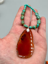 Load image into Gallery viewer, This unique and luxurious Amber Tone Agate Geode Sliced Stone Chip Necklace is a one-of-a-kind statement piece crafted from natural gemstones. The necklace features an amber-tone banded geode, suspended from a strand of blue and green turquoise and gold glass beads, and blue-green magnesite stone beads. This stylish boho-chic accessory is perfect for any casual or formal occasion. Measurements: Necklace is 18” in length - pendant is 2 1/2” Height