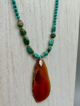 Load image into Gallery viewer, This unique and luxurious Amber Tone Agate Geode Sliced Stone Chip Necklace is a one-of-a-kind statement piece crafted from natural gemstones. The necklace features an amber-tone banded geode, suspended from a strand of blue and green turquoise and gold glass beads, and blue-green magnesite stone beads. This stylish boho-chic accessory is perfect for any casual or formal occasion. Measurements: Necklace is 18” in length - pendant is 2 1/2” Height
