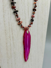 Load image into Gallery viewer, Unlock your inner goddess with this stunning Large Fuchsia Agate Geode Sliced Stone Chip Necklace. Featuring a vibrant fuchsia agate geode pendant surrounded by Rhodonite stone chips and gold and black glass beading, the silver leaf bail completes this chic and boho-inspired look. Make a bold statement with this bohemian-style gemstone necklace. Measurements: Necklace is 17 3/4” in length - pendant is 3” Height