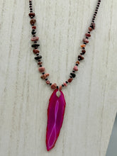 Load image into Gallery viewer, Unlock your inner goddess with this stunning Large Fuchsia Agate Geode Sliced Stone Chip Necklace. Featuring a vibrant fuchsia agate geode pendant surrounded by Rhodonite stone chips and gold and black glass beading, the silver leaf bail completes this chic and boho-inspired look. Make a bold statement with this bohemian-style gemstone necklace. Measurements: Necklace is 17 3/4” in length - pendant is 3” Height