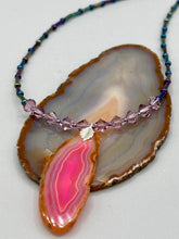 Load image into Gallery viewer, Make a bold style statement with this eye-catching Soft Pink and Amber Agate Geode Sliced Stone Chip Necklace. Featuring a vibrant soft pink and amber tone agate geode pendant surrounded by dark blue glass beads with iridescent tones of purple, blue, green, pink and gold. This bohemian-style gemstone necklace is the perfect way to add a unique touch of shabby boho chic to any look.   Measurements:    Necklace is 18” in length - pendant is 2 1/4” Height