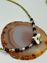 Load image into Gallery viewer, This beautiful Bee Pendant With Black and Yellow Beaded Necklace is the perfect accessory for any summer outfit. The vibrant colors will make a bold statement, while the black and gold blend adds a subtle elegance. Its perfect for any nature lover, hippie, or witchy style.  Measurements:  Necklace is 18”