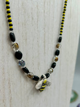 Load image into Gallery viewer, This beautiful Bee Pendant With Black and Yellow Beaded Necklace is the perfect accessory for any summer outfit. The vibrant colors will make a bold statement, while the black and gold blend adds a subtle elegance. Its perfect for any nature lover, hippie, or witchy style.  Measurements:  Necklace is 18”
