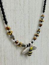 Load image into Gallery viewer, This beautiful Bee Pendant With Black and Yellow Beaded Necklace is the perfect accessory for any summer outfit. The vibrant colors will make a bold statement, while the black and gold blend adds a subtle elegance. Its perfect for any nature lover, hippie, or witchy style.   Measurements:   Necklace is 18”