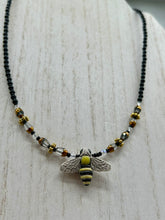 Load image into Gallery viewer, This beautiful Bee Pendant With Black and Yellow Beaded Necklace is the perfect accessory for any summer outfit. The vibrant colors will make a bold statement, while the black and gold blend adds a subtle elegance. Its perfect for any nature lover, hippie, or witchy style.   Measurements:   Necklace is 18”