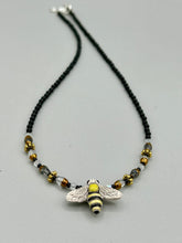 Load image into Gallery viewer, This beautiful Bee Pendant With Black and Yellow Beaded Necklace is the perfect accessory for any summer outfit. The vibrant colors will make a bold statement, while the black and gold blend adds a subtle elegance. Its perfect for any nature lover, hippie, or witchy style.   Measurements:   Necklace is 18”