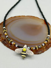 Load image into Gallery viewer, This beautiful Bee Pendant With Black and Yellow Beaded Necklace is the perfect accessory for any summer outfit. The vibrant colors will make a bold statement, while the black and gold blend adds a subtle elegance. Its perfect for any nature lover, hippie, or witchy style.   Measurements:   Necklace is 18”