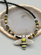 Load image into Gallery viewer, This beautiful Bee Pendant With Black and Yellow Beaded Necklace is the perfect accessory for any summer outfit. The vibrant colors will make a bold statement, while the black and gold blend adds a subtle elegance. Its perfect for any nature lover, hippie, or witchy style.   Measurements:   Necklace is 18”