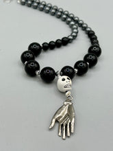 Load image into Gallery viewer, This elegant Peruvian ceramic skull beaded necklace is the perfect accessory for your unique look. With a large skull bead and a lucky hand charm, it exudes a dark, alluring vibe. Complemented with black glass and hematite stone beads, it will make a bold statement. Measurements: Necklace: 19” in length - skulls with lucky hand charm is 2 3/4” Height