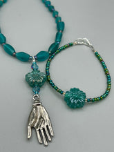Load image into Gallery viewer, This blue-green pressed glass floral beaded bracelet is a nature-inspired accessory that adds a hint of summer to any look. Crafted with intricate green-blue pressed glass beads and metal wire, the bracelet has an iridescent shimmer finish and a lobster claw clasp for secure wear. Perfect for day-to-night looks.  Measurements:  Bracelet: 8 1/2" in length