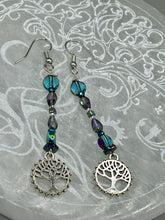 Load image into Gallery viewer, This captivating set of earrings boasts an exquisite range of intense blues and purples, accented with a warm touch of gold and green. The dangling silver plated tree of life charm adds a beautiful finishing touch.  Measurements: 2 1/2” in length